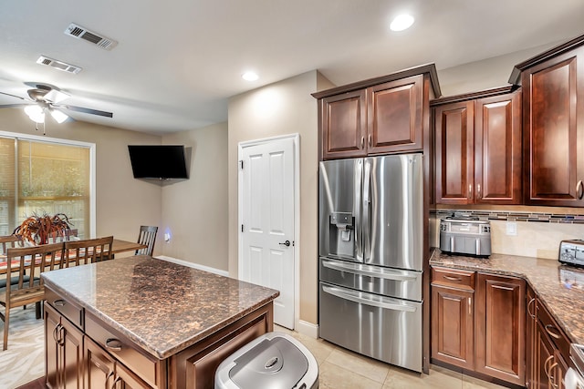 kitchen with decorative backsplash, dark stone counters, visible vents, and stainless steel fridge