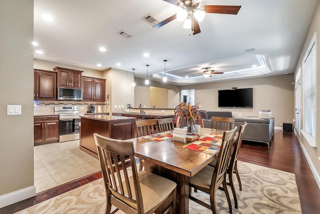 dining space featuring recessed lighting, visible vents, ceiling fan, and a tray ceiling