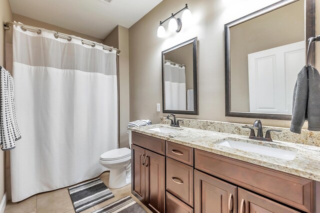 full bathroom with a sink, toilet, double vanity, and tile patterned floors