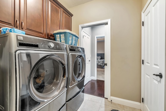 laundry area with light tile patterned floors, cabinet space, baseboards, and washing machine and clothes dryer