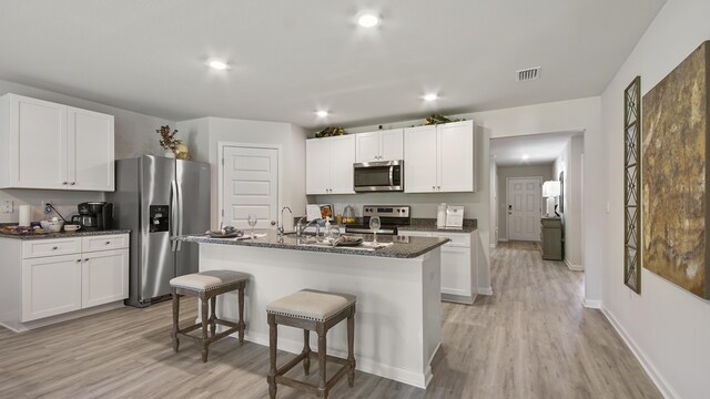 217 Eunola Ln, Freeport, FL 32439 - kitchen with a kitchen breakfast bar, white cabinetry, stainless steel appliances, light wood-type flooring, and an island with sink