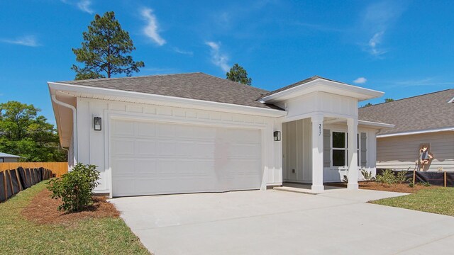 217 Eunola Ln, Freeport, FL 32439 - view of front of house with board and batten siding, fence, a shingled roof, a garage, and driveway