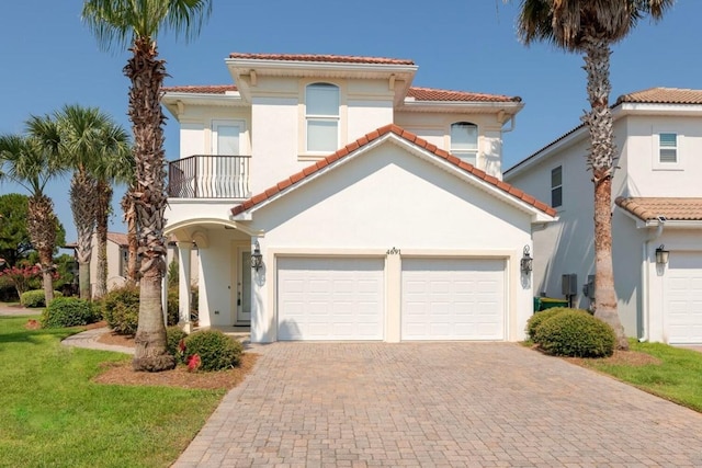 mediterranean / spanish-style house featuring stucco siding, a tiled roof, decorative driveway, and a balcony