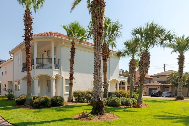 view of side of property featuring a balcony, a yard, a residential view, and stucco siding