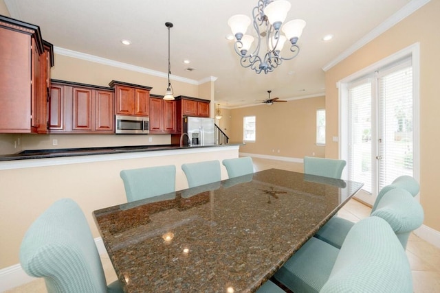 kitchen featuring hanging light fixtures, appliances with stainless steel finishes, a breakfast bar, and ornamental molding