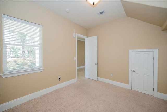 unfurnished bedroom featuring visible vents, baseboards, carpet, and vaulted ceiling