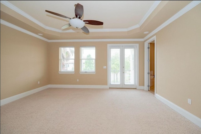 unfurnished room with a tray ceiling, crown molding, baseboards, and light carpet