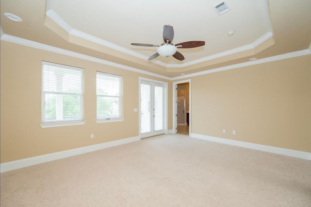 empty room featuring baseboards, a tray ceiling, light carpet, and visible vents