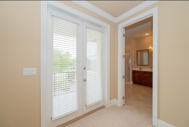 doorway to outside featuring ornamental molding, a sink, french doors, baseboards, and light colored carpet