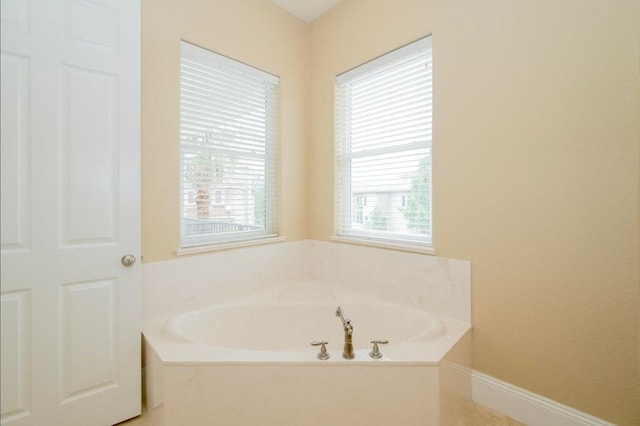 bathroom featuring baseboards and a bath