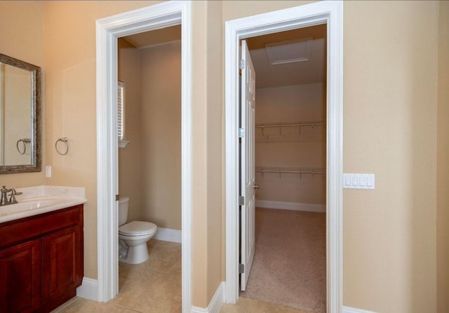 bathroom featuring toilet, tile patterned flooring, baseboards, a spacious closet, and vanity