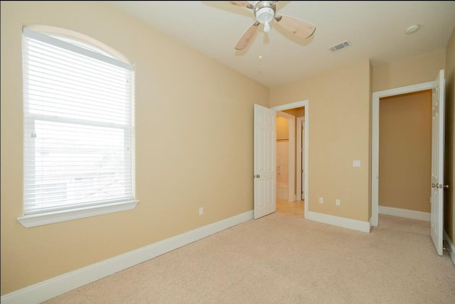 unfurnished bedroom with light colored carpet, baseboards, visible vents, and ceiling fan