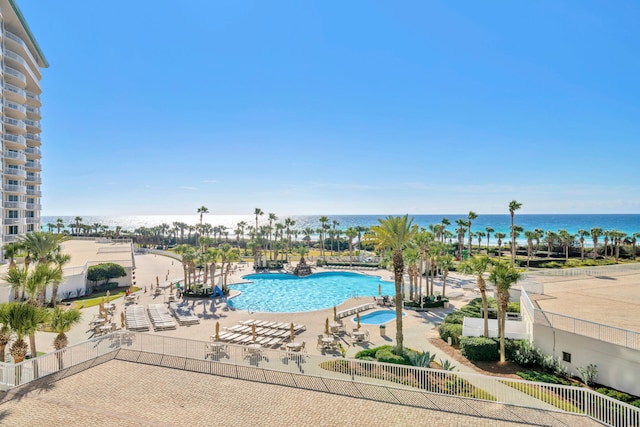 pool featuring a patio, fence, and a water view