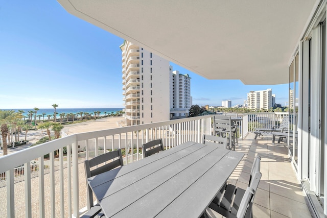 balcony with a water view, outdoor dining space, and a view of city