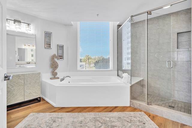 full bath with a stall shower, vanity, a garden tub, and wood finished floors