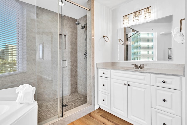 full bathroom featuring a shower stall, vanity, a garden tub, and wood finished floors