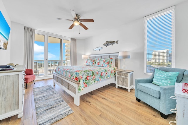 bedroom featuring multiple windows, expansive windows, wood finished floors, and access to outside