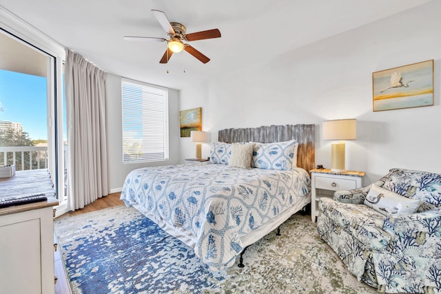 bedroom featuring access to exterior, multiple windows, ceiling fan, and wood finished floors