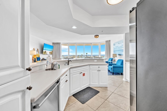 kitchen featuring light tile patterned floors, a sink, stainless steel appliances, light countertops, and white cabinets