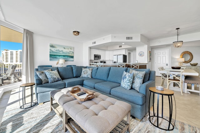 living area featuring light tile patterned floors, visible vents, and a wall of windows