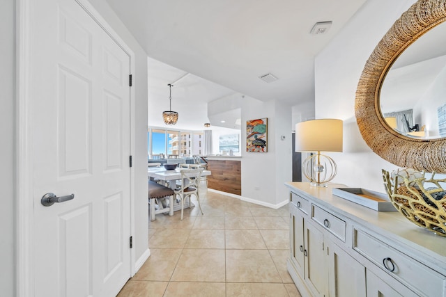 hallway featuring light tile patterned floors, baseboards, and visible vents