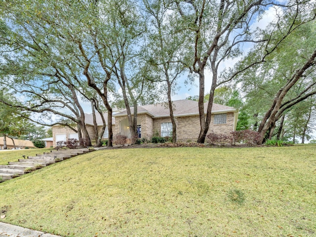 view of front of home with a front yard, an attached garage, and brick siding