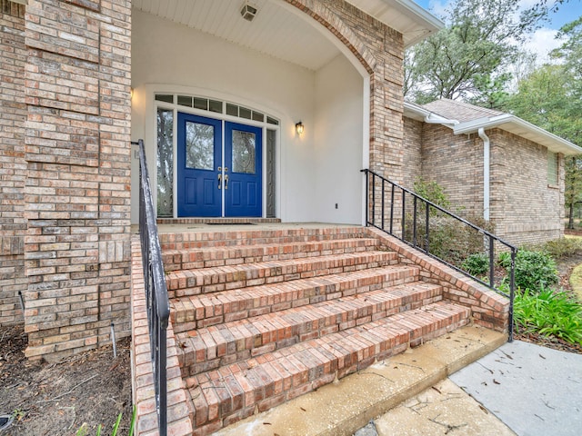 view of exterior entry with brick siding and a shingled roof