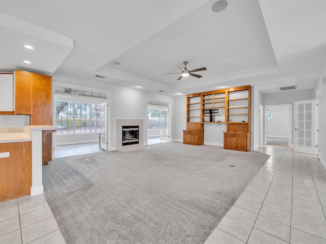 unfurnished living room with visible vents, a raised ceiling, and light carpet