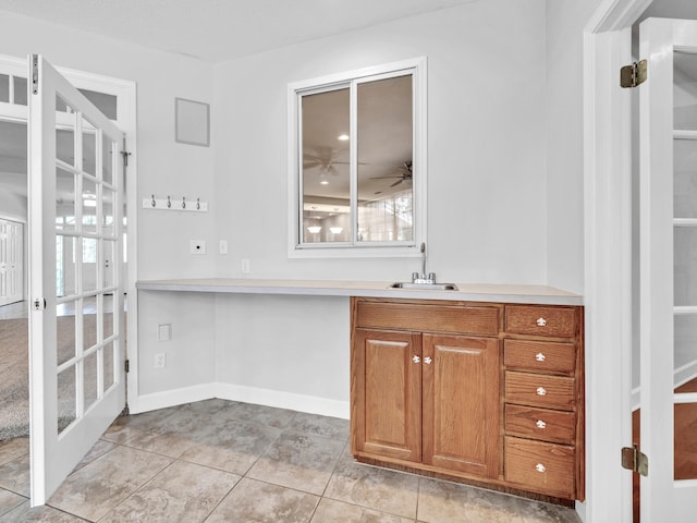 interior space with a sink, french doors, baseboards, and light tile patterned floors