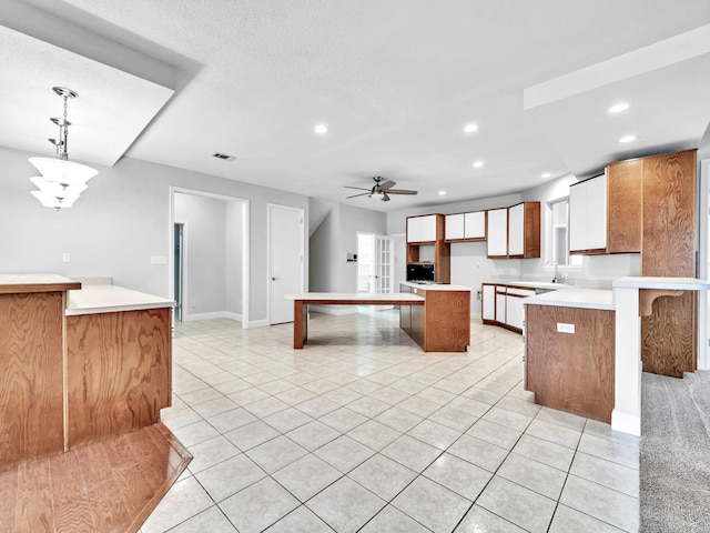 kitchen featuring a center island, light tile patterned floors, recessed lighting, a peninsula, and a sink