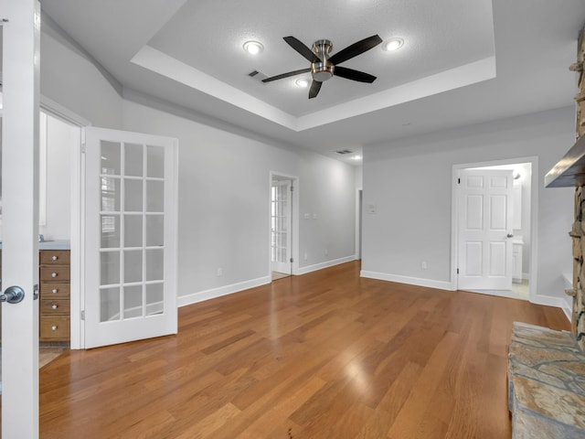 empty room with visible vents, a raised ceiling, baseboards, and wood finished floors