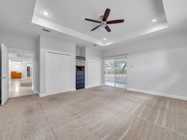 unfurnished living room featuring a tray ceiling, baseboards, visible vents, and carpet flooring