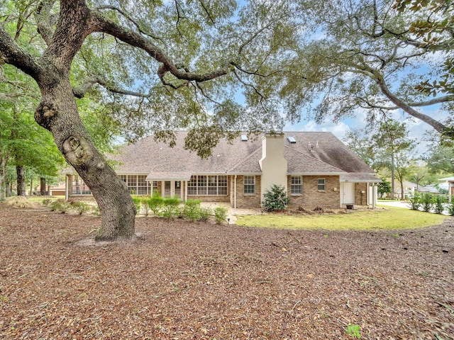 rear view of property with a patio, brick siding, roof with shingles, and a lawn