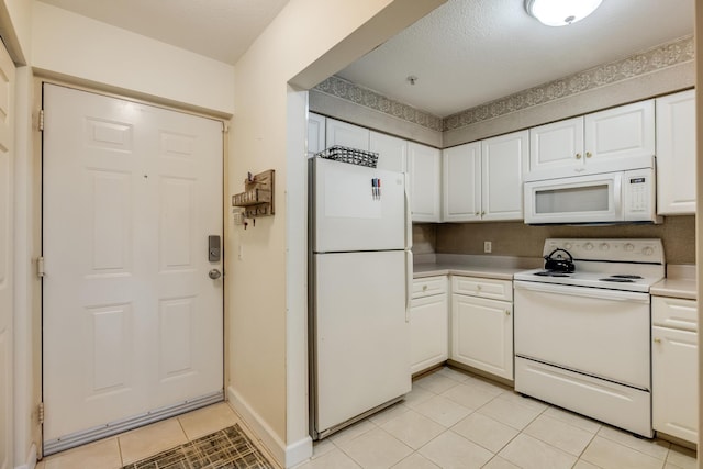 kitchen with light tile patterned flooring, white appliances, and white cabinetry