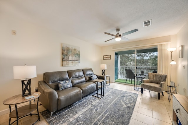 living room with baseboards, visible vents, light tile patterned flooring, ceiling fan, and a textured ceiling