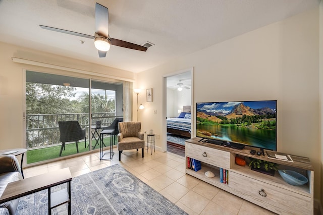 living area featuring tile patterned flooring, a ceiling fan, and baseboards