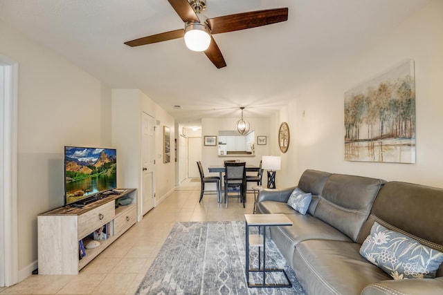 living room with light tile patterned floors, a ceiling fan, and baseboards