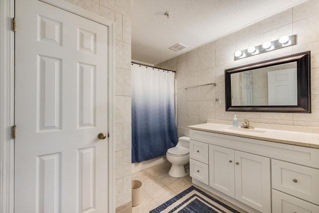 bathroom with visible vents, a textured ceiling, tile walls, tile patterned flooring, and vanity