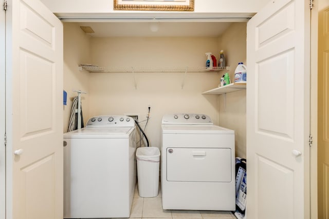 laundry area with washer and clothes dryer, laundry area, and light tile patterned floors