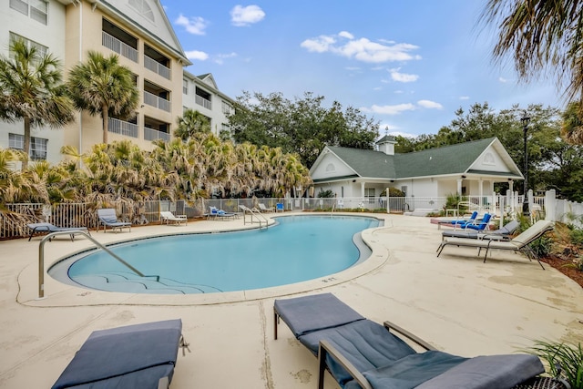 community pool with a patio area and fence