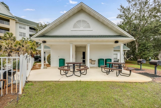 rear view of house with a yard, roof with shingles, a patio, and fence