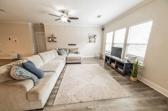 living area featuring visible vents, wood finished floors, baseboards, and ornamental molding