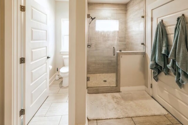 full bathroom featuring a shower stall, toilet, a healthy amount of sunlight, and tile patterned floors