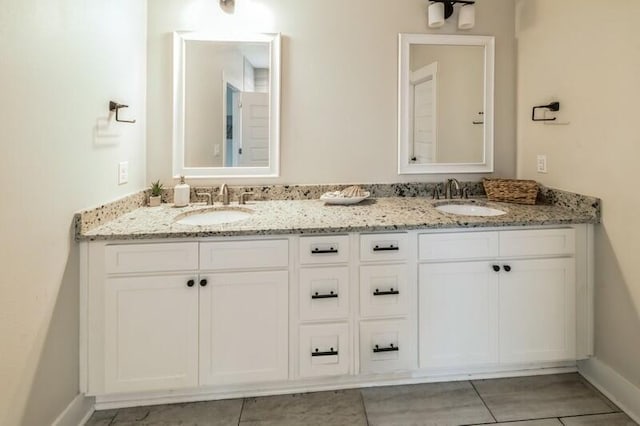 full bath with double vanity, tile patterned floors, baseboards, and a sink