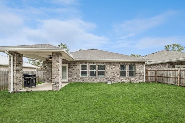 back of house featuring a yard, a patio, brick siding, and a fenced backyard