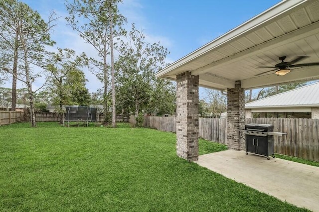 view of yard with a fenced backyard, a patio area, a ceiling fan, and a trampoline