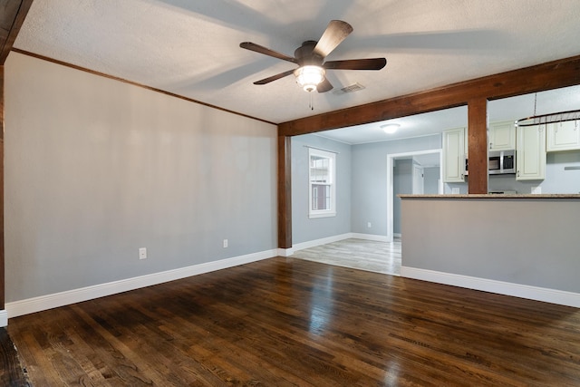 unfurnished living room featuring visible vents, ornamental molding, hardwood / wood-style floors, baseboards, and ceiling fan