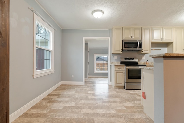 kitchen with plenty of natural light, appliances with stainless steel finishes, baseboards, and light stone countertops