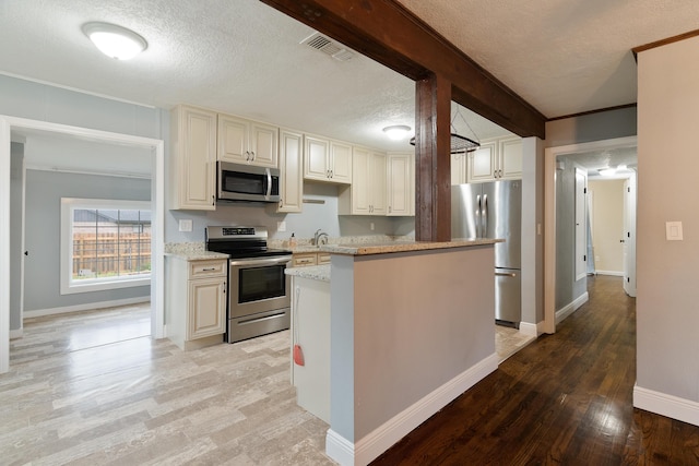 kitchen featuring visible vents, stainless steel appliances, light wood-style floors, a textured ceiling, and a sink