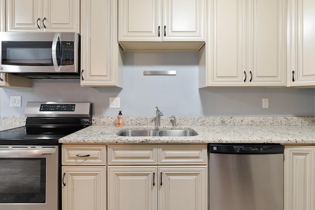 kitchen featuring light stone countertops, stainless steel appliances, and a sink